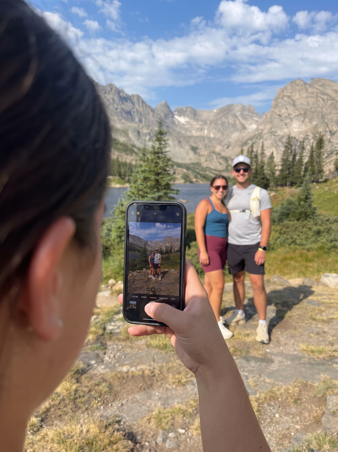 A phone taking a photo of a couple at a mountain lake
