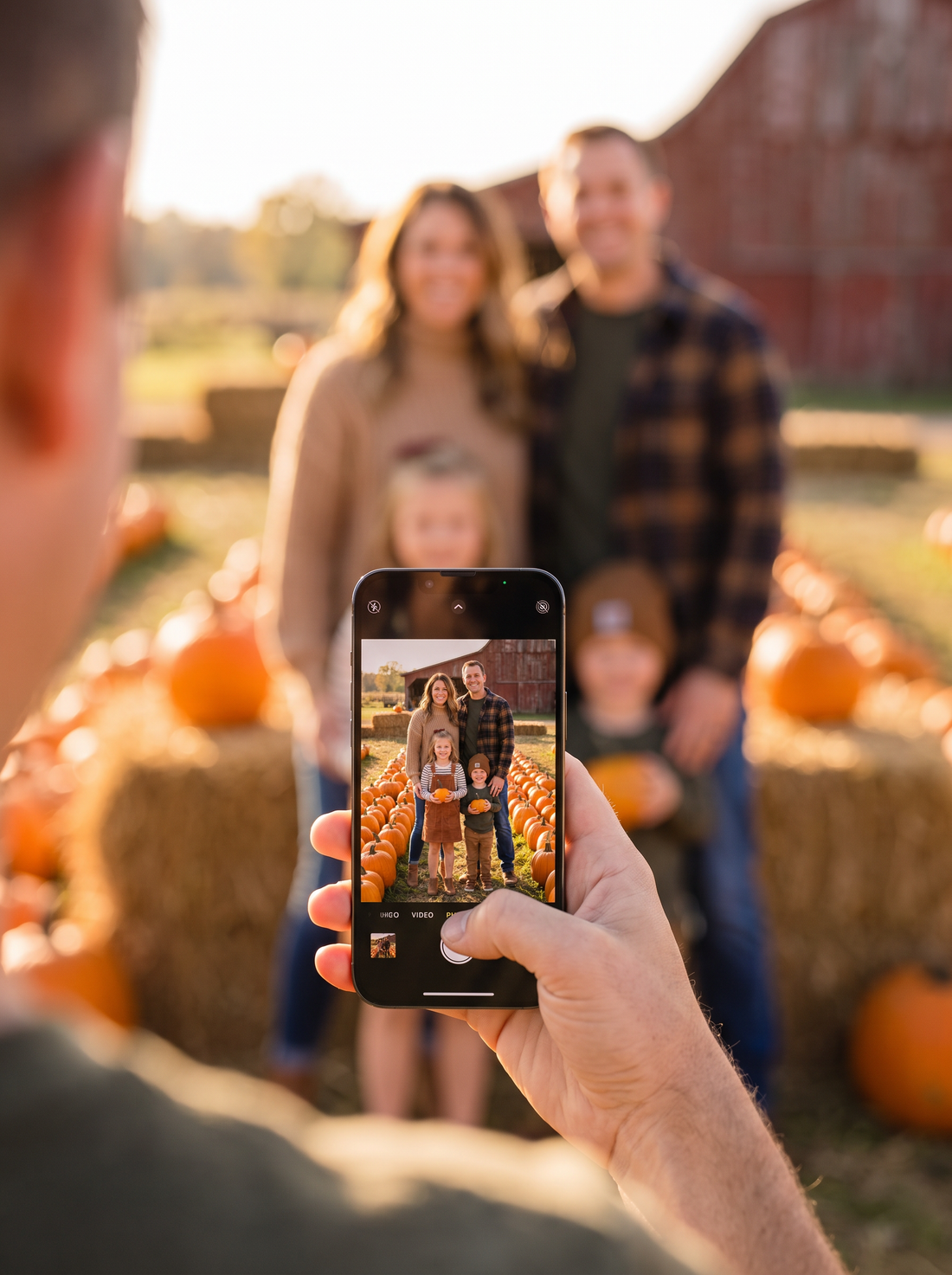 A phone taking a family photo at a pumpkin patch